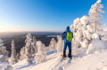 Hiker with snowshoes on top of a snowy hill.