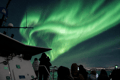 Guests watching bright green Northern Lights from a boat off the coast of Reykjavík.