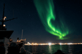 A vivid green Northern Lights display seen from a boat off the coast of Reykjavík.