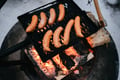 Makkara sausages cooking on a grill over a campfire in Rovaniemi, Lapland